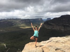 woman standing on cliff doing yoga pose